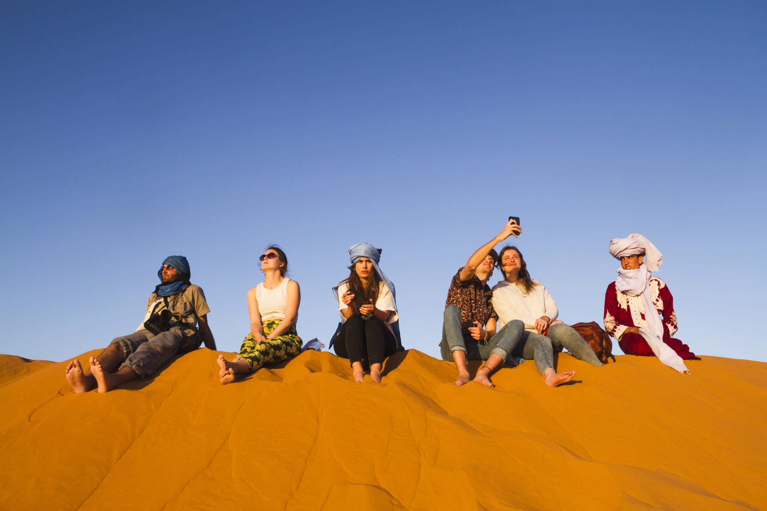 group-people-sitting-top-dune small group tours in Morocco